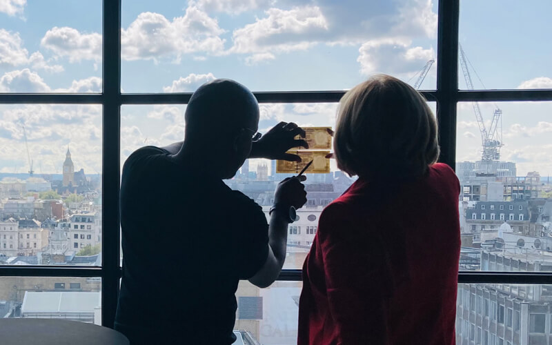 two colleagues inspect a bank note by holding it up to the light