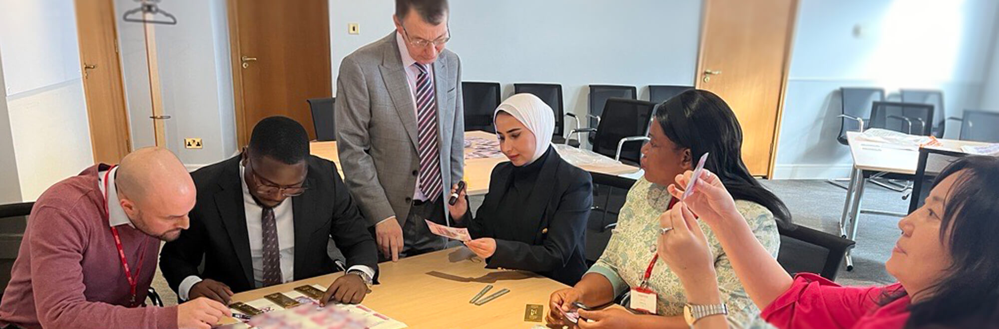 a group of advocates gather around a table in a board room analysing various bank notes to learn how to spot a counterfeit