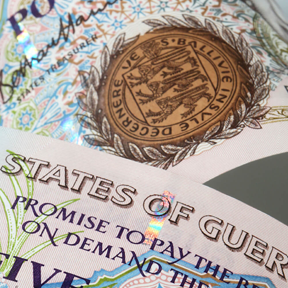a brown and green five pound Guernsey bank note featuring the three lions of England