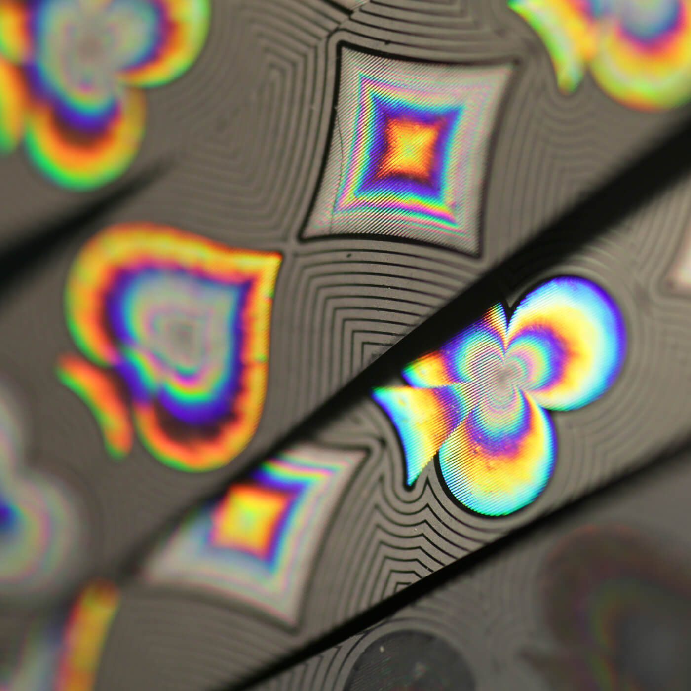 a series of highly elaborate fluorescent security patterns featuring the card symbols of spades, clubs, hearts and diamonds