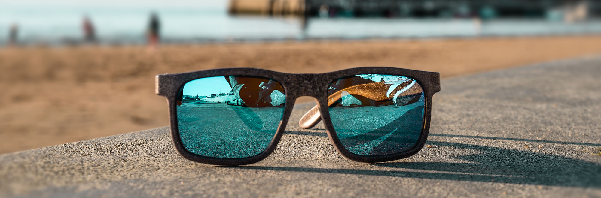 a pair of sunglasses made out of recycled plastic rest on top of a concrete wall at the beach