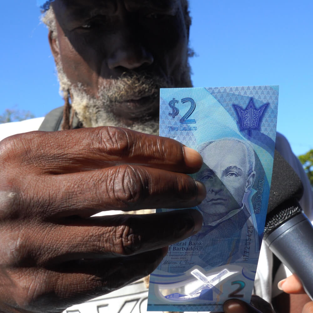 a member of the public inspects a new Barbadian two dollar bank note