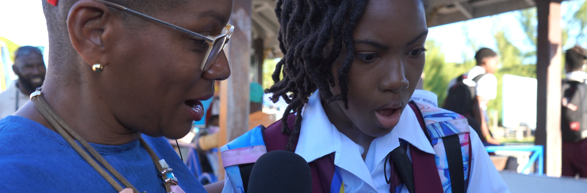 a teacher and a school girl gasp in awe whilst looking at a new Barbadian bank note