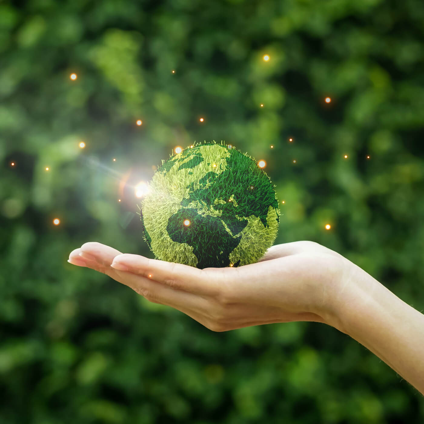 a composite image where a pale hand holds planet earth made out of grass